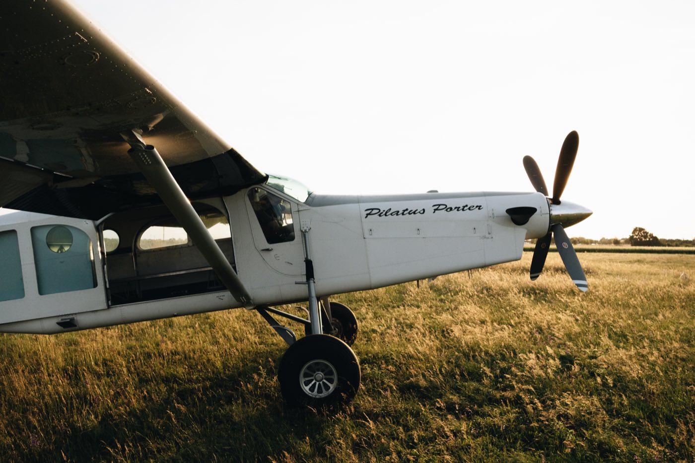 Un Pilatus Porter au sol sur l'herbe, en fin de journée